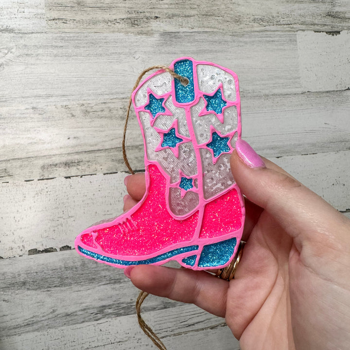 A wooden background with a boot car freshie in pink and blue