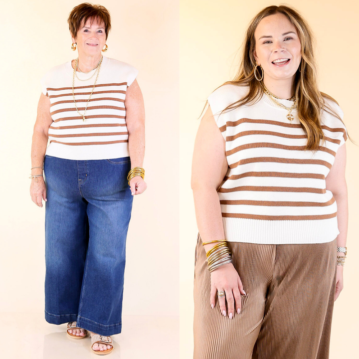Two women wearing matching tan and white striped shirts and jeans on a plain background