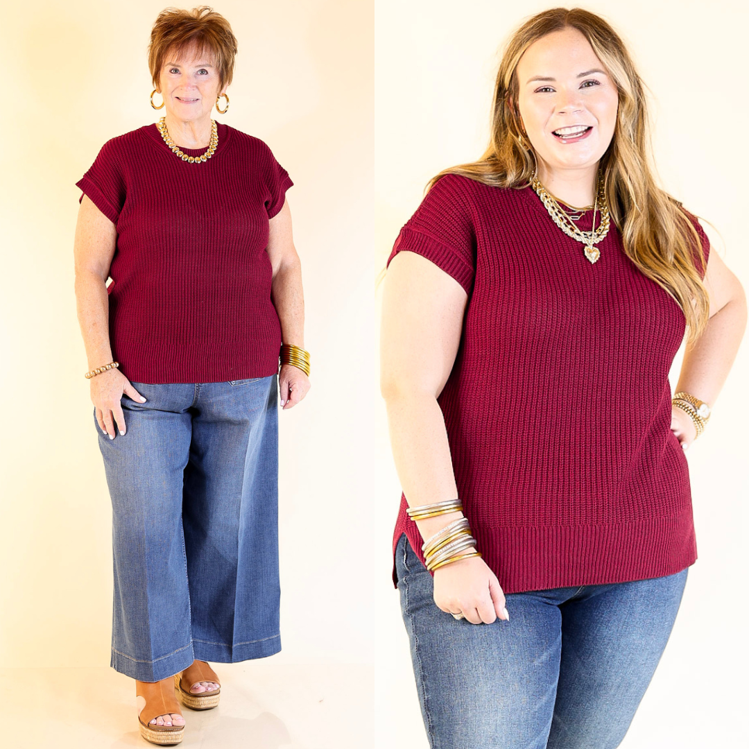 Two women wearing maroon sweater tops and blue jeans against a plain background