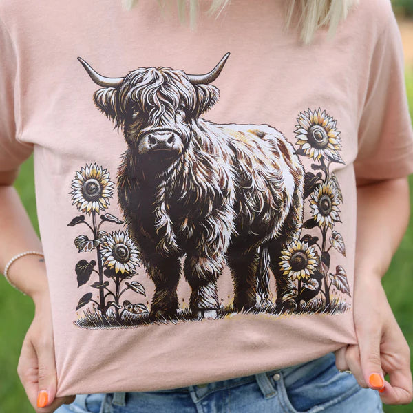 Person wearing a t-shirt with a highland cow and sunflower design.