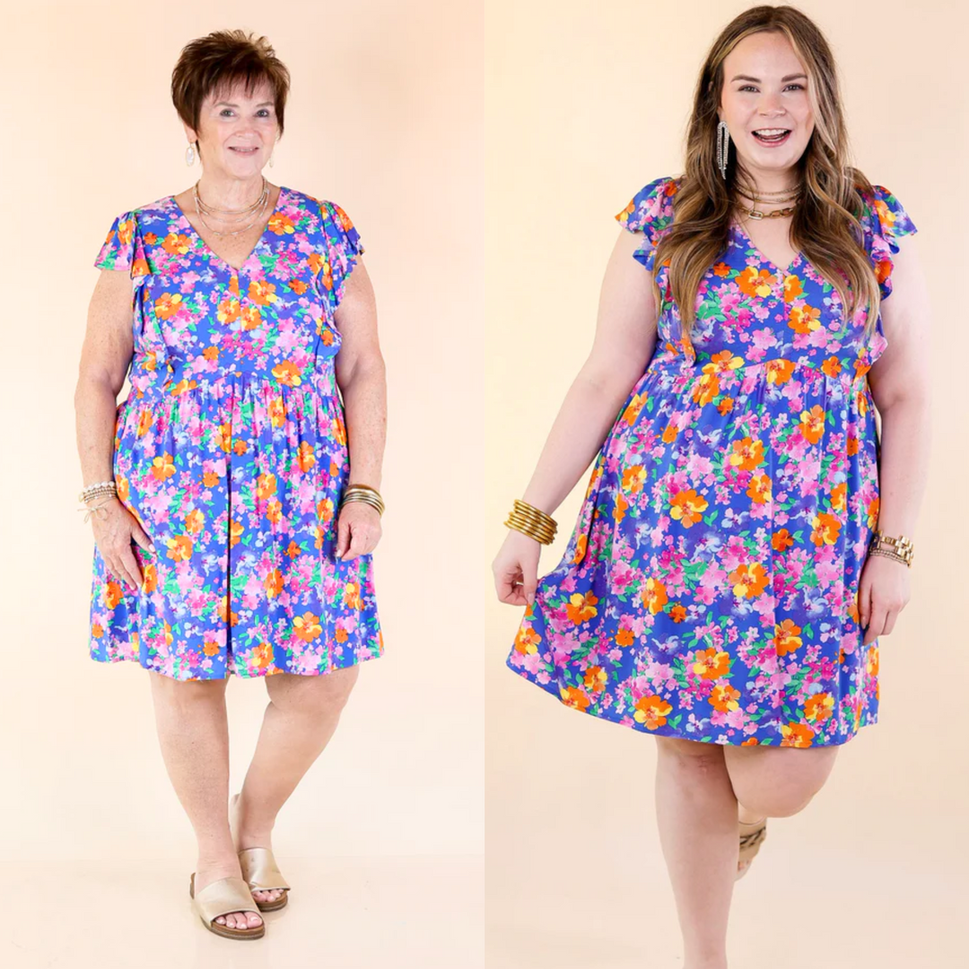 Adorned with a vibrant pink, yellow, and green floral print against a serene blue background and ruffle cap sleeves. Dress is fully lined. Small to plus sizes.