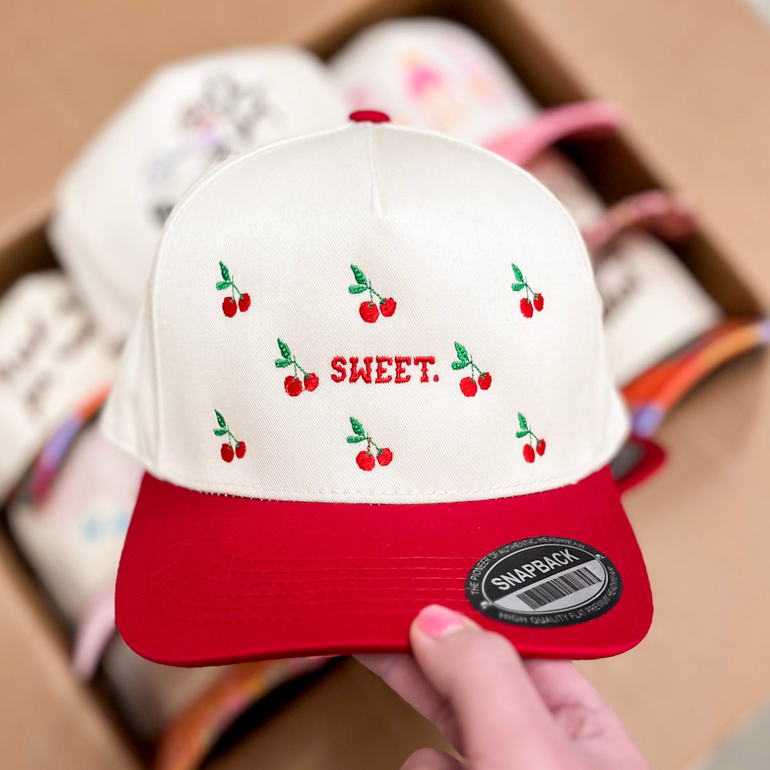 White and red cap with cherry designs and &