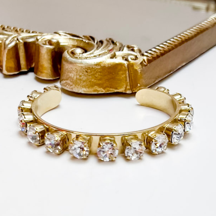 Gold earring with clear gemstones on a white background