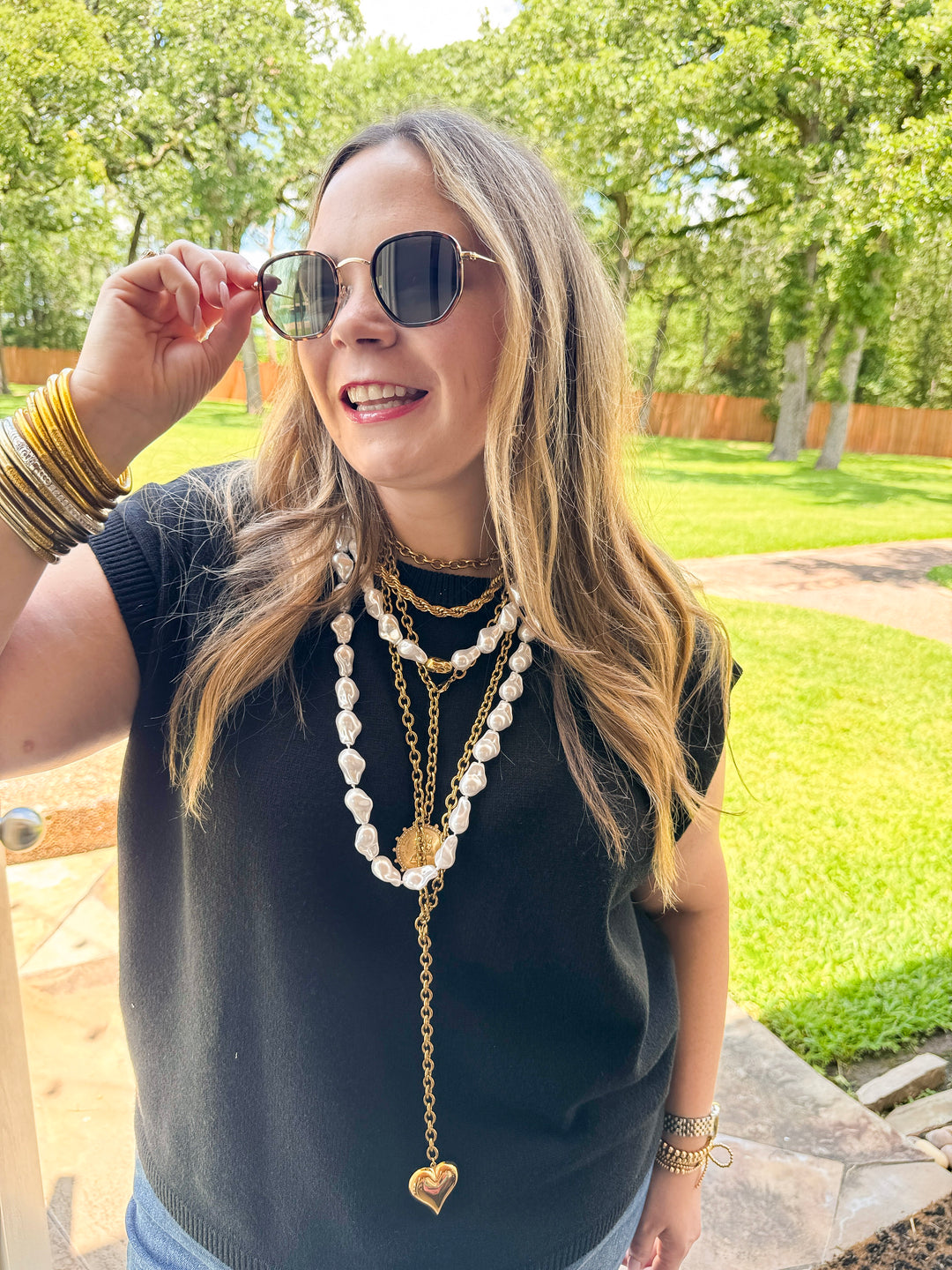 Woman wearing sunglasses and layered necklaces outdoors