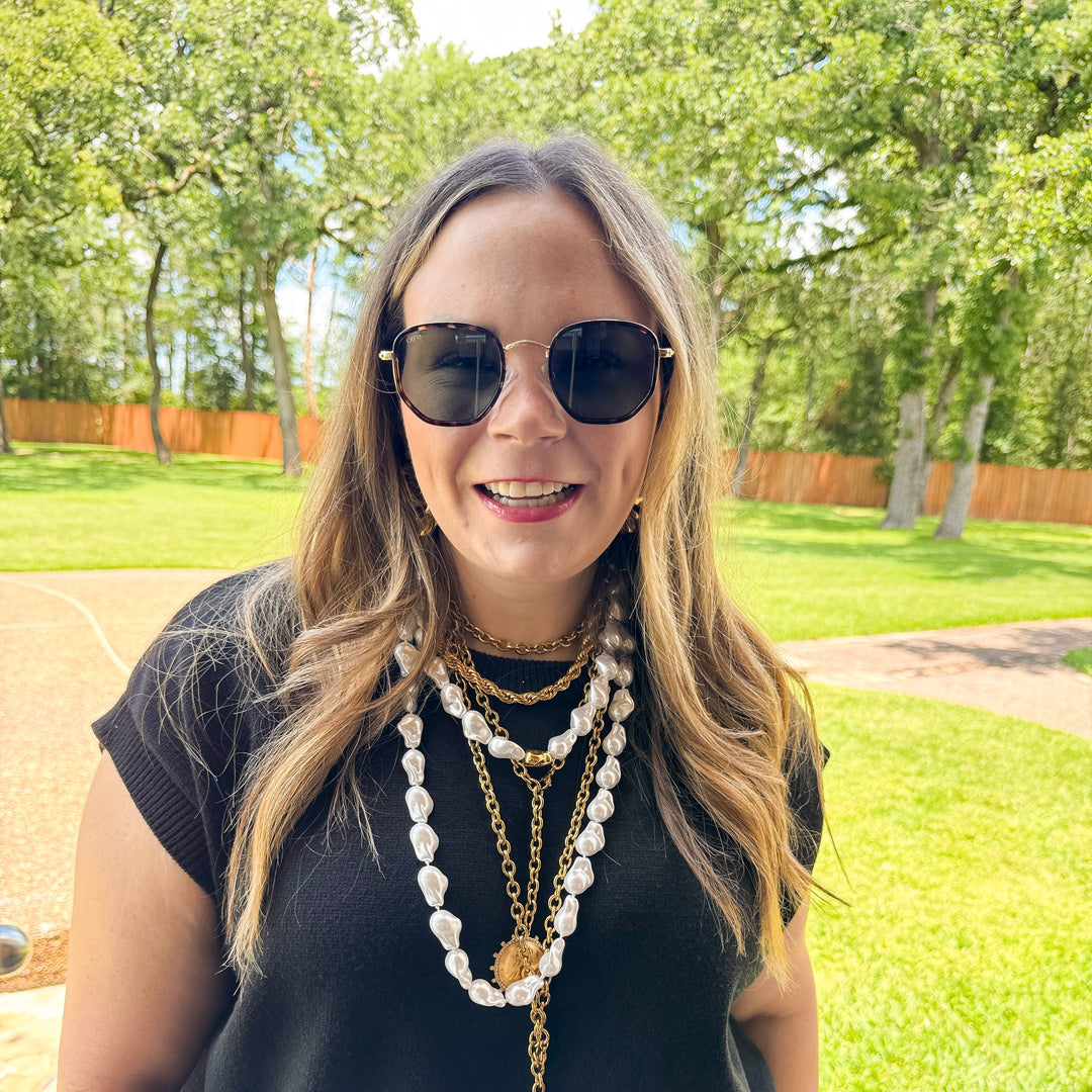 Woman wearing sunglasses and layered necklaces outdoors