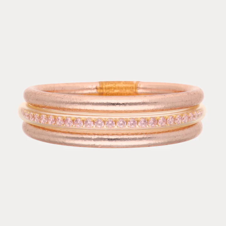 Set of rose gold and pink bangles on a light beige background