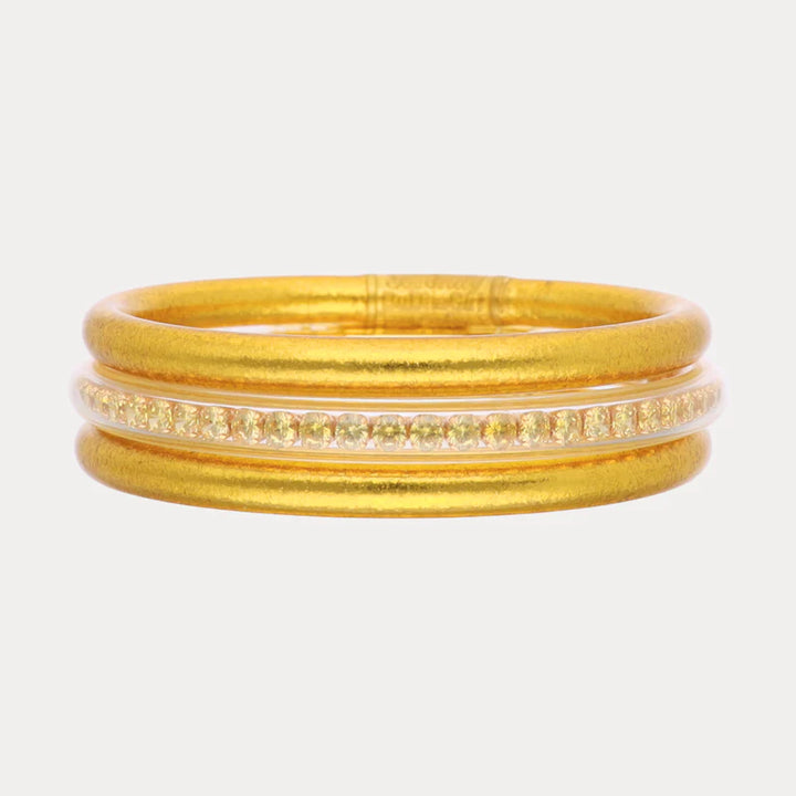 Set of gold bangles on a light gray background