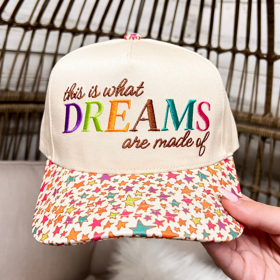 Cap with colorful star pattern and embroidered text held by a hand against a neutral background