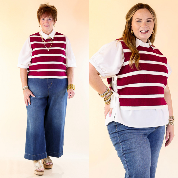 Two women wearing matching Maroon and white striped vests and blue jeans on a beige background.