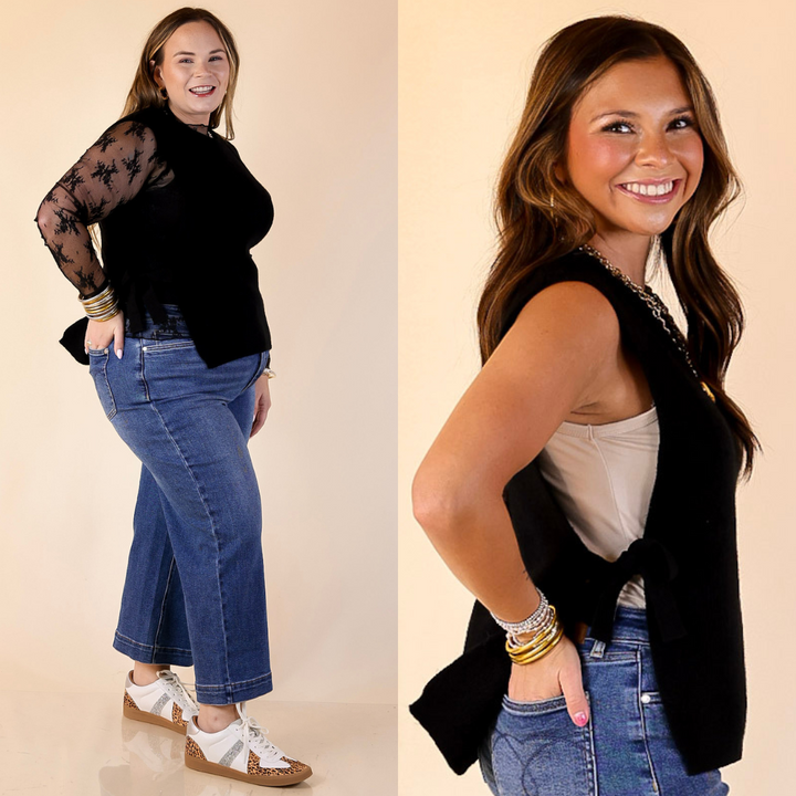 Women wearing a black vest featuring bow tie detailing and jeans against a beige backdrop