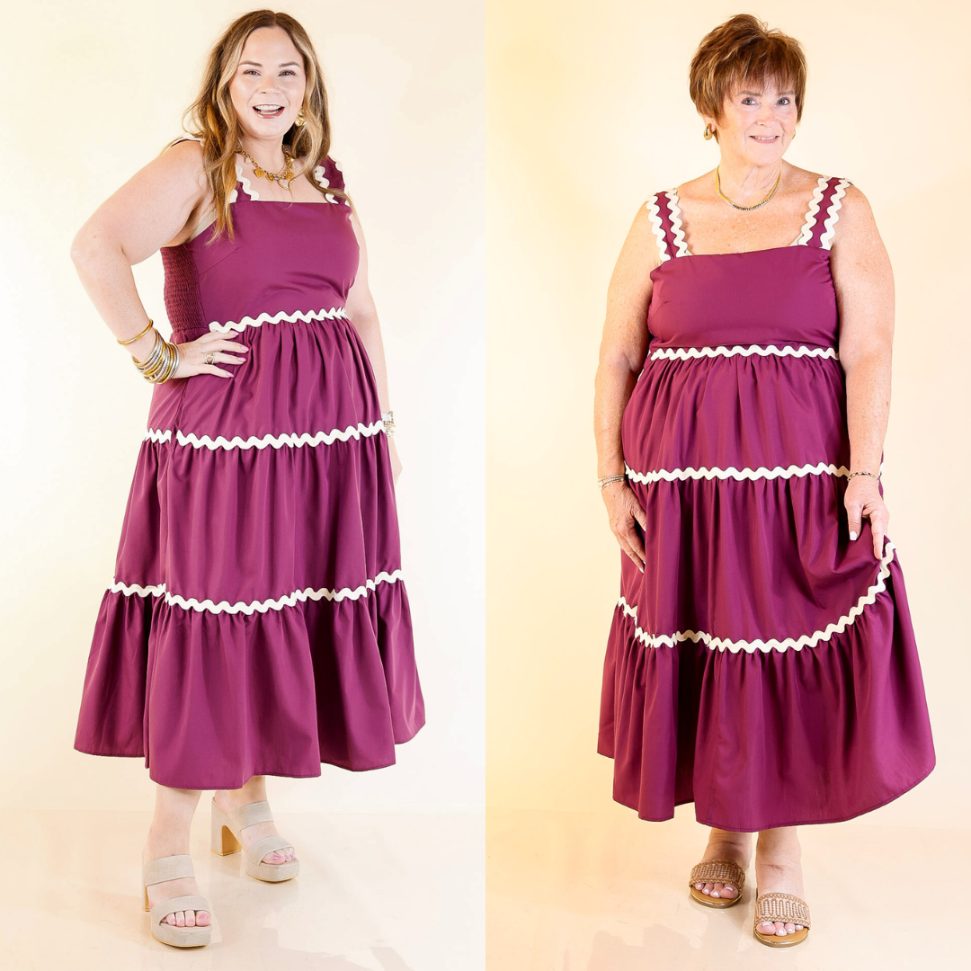 Two women wearing matching purple dresses with white trim against a beige background