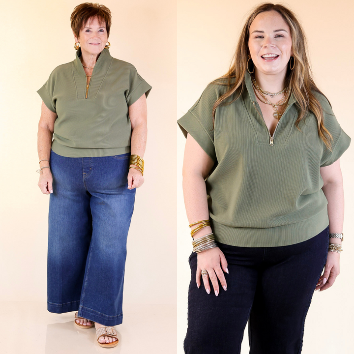 Two women wearing green tops and dark pants against a beige background