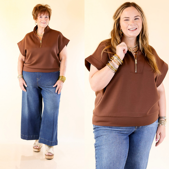 Two women wearing brown tops and blue jeans on a beige background