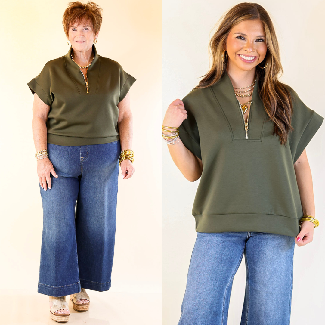 Two women wearing a olive green top and blue jeans against a plain background