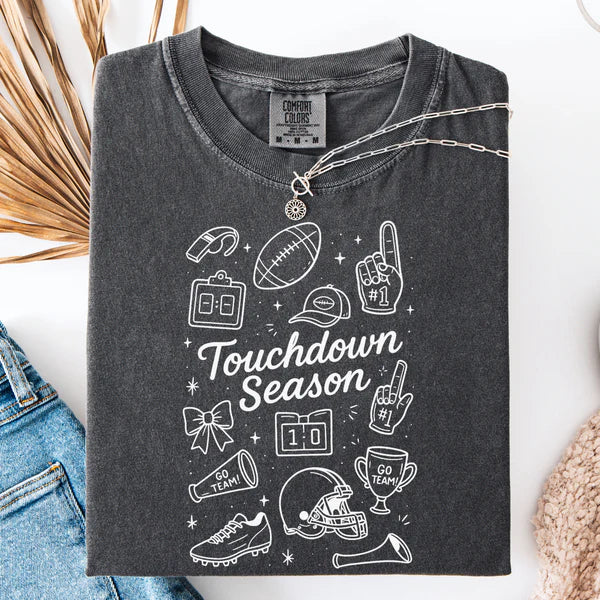 Dark gray t-shirt with 'Touchdown Season' design on a white surface with denim jeans and a necklace.