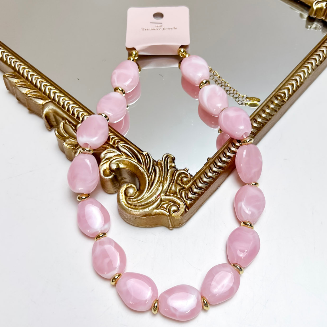 Treasure Jewels light pink oval beaded necklace featuring glossy marbled beads with polished gold spacer accents and an adjustable chain extension.