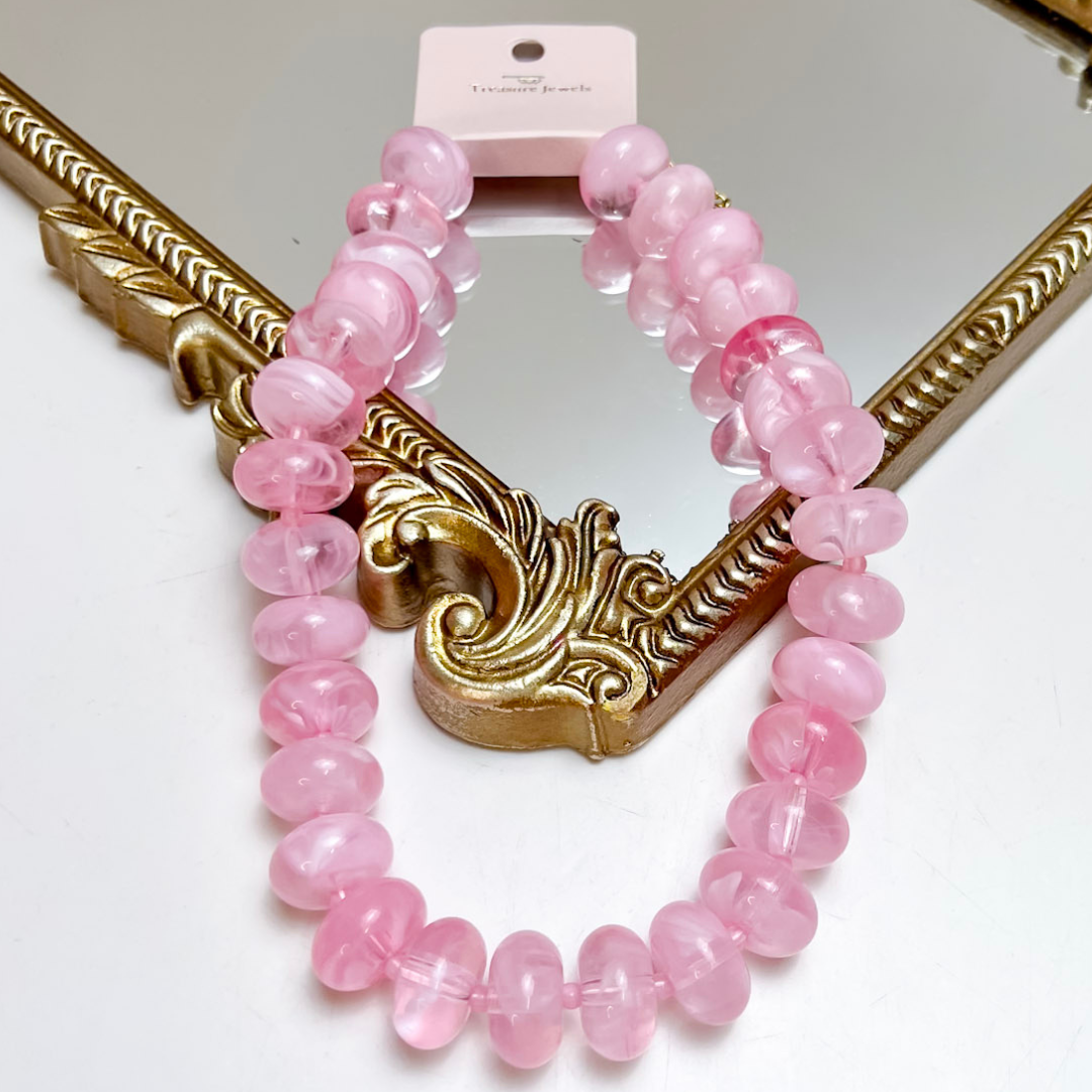 Treasure Jewels light pink beaded necklace featuring glossy translucent donut-shaped beads with an adjustable chain extension.