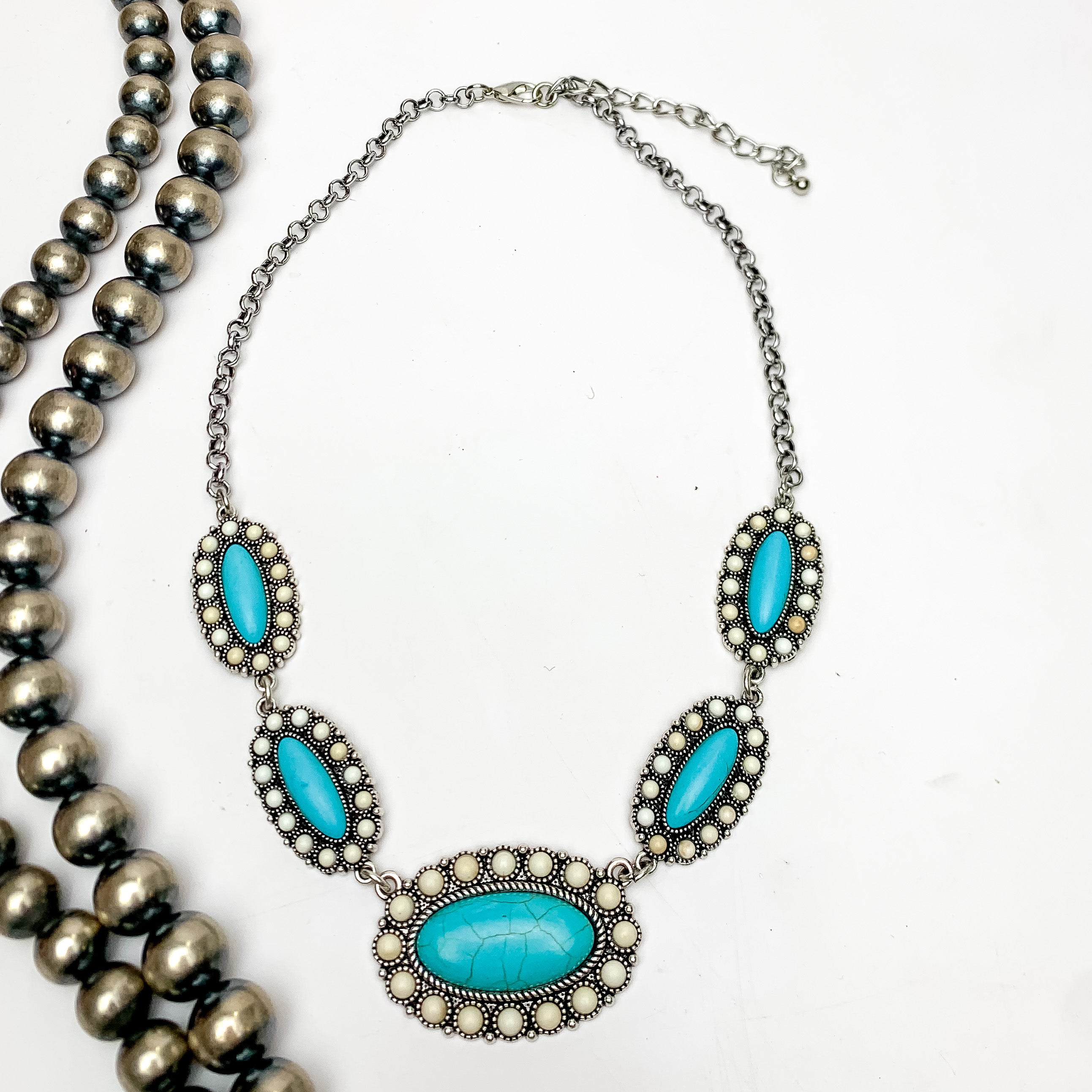 Western Silver Tone Necklace in turquoise blue and ivory. This necklace is on a white background with Navajo pearls on the left.