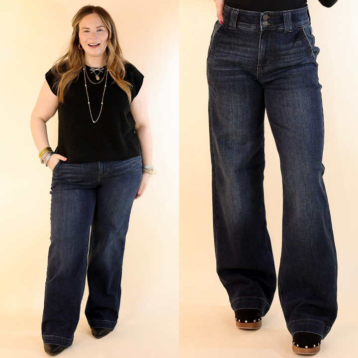 Models wearing a pair of dark wash, high-waisted, wide-leg jeans with a double-button fly closure.