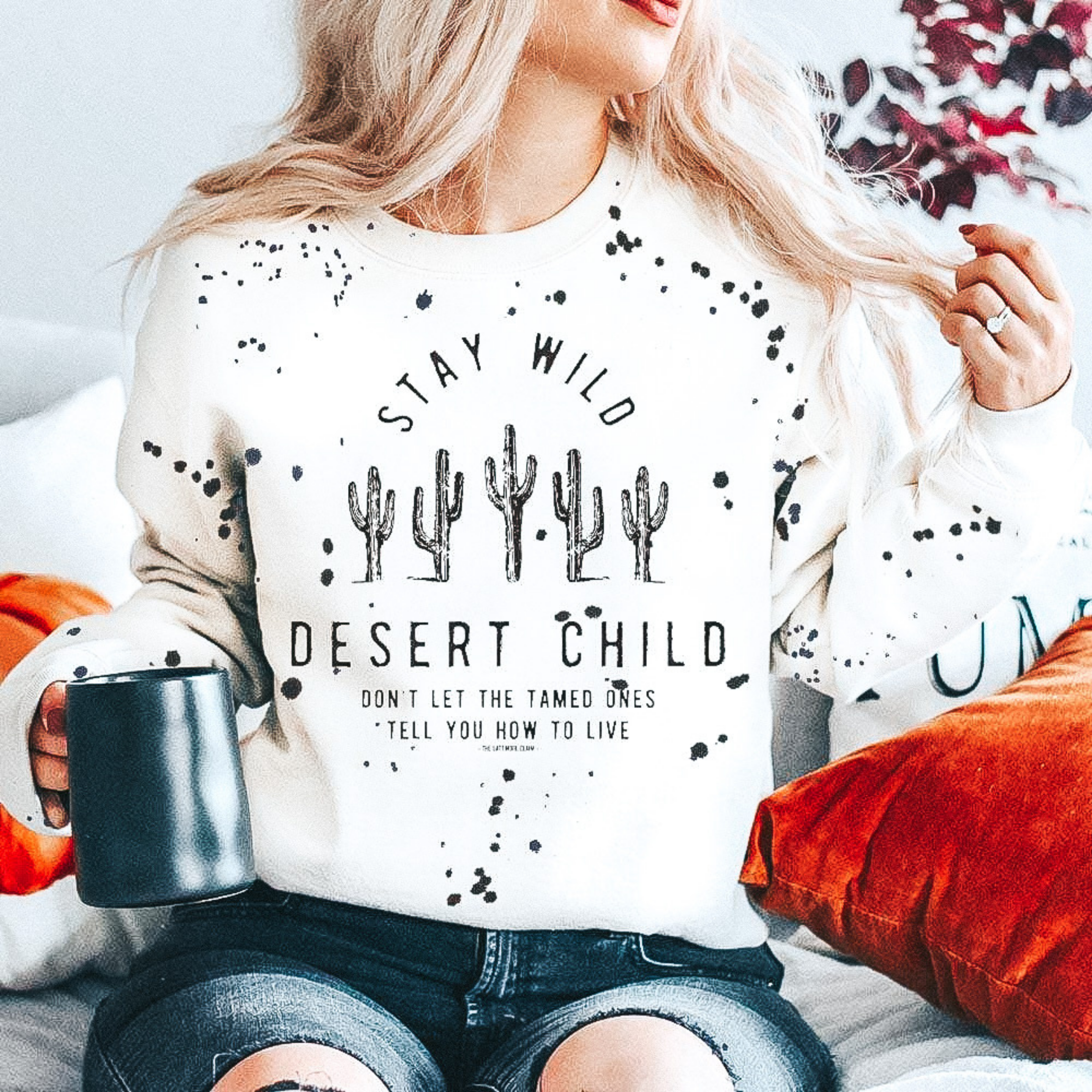 Model is wearing a black graphic tee with the saying "Stay Wild Desert Child Don't Let The Tamed Ones Tell You How To Live" in black. 
