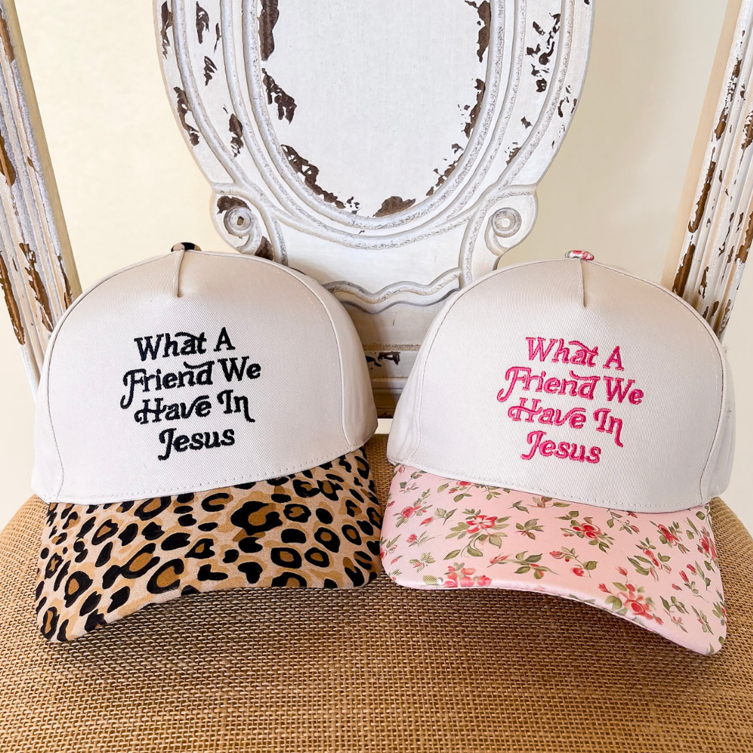 Cream embroidered What a Friend We Have in Jesus trucker hat available with floral or leopard print brim options.