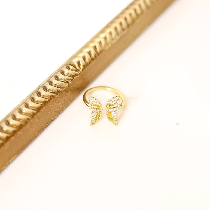 Gold ring with butterfly design on a white background