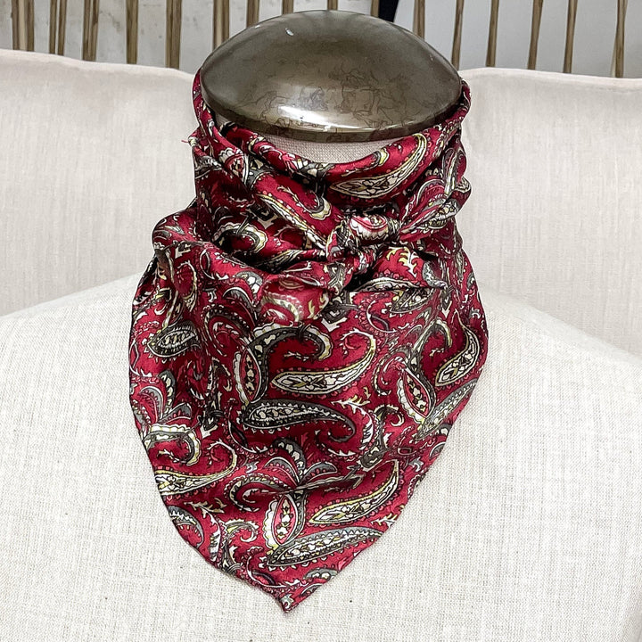A paisley print wild rag in wine and olive, tied around the neck of a mannequin.