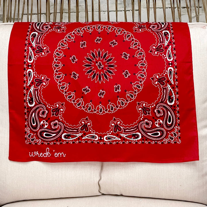 Red bandana with white patterns on a white pillow in a wicker chair