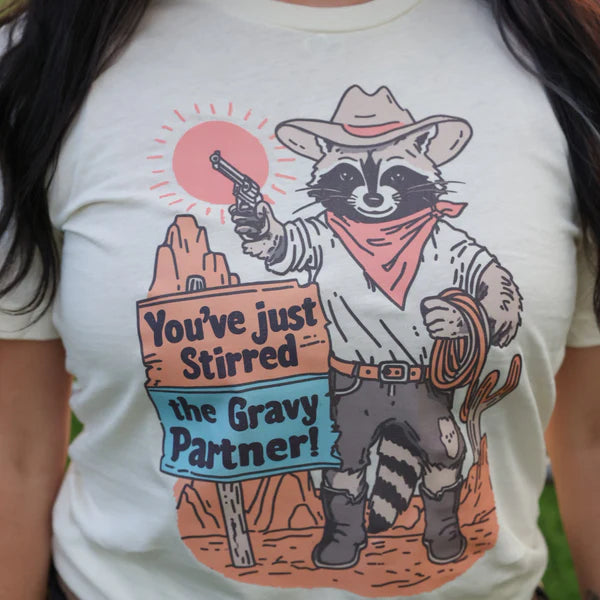 T-shirt with a raccoon cowboy graphic and text 'You've just stirred the gravy partner!' on a white background.