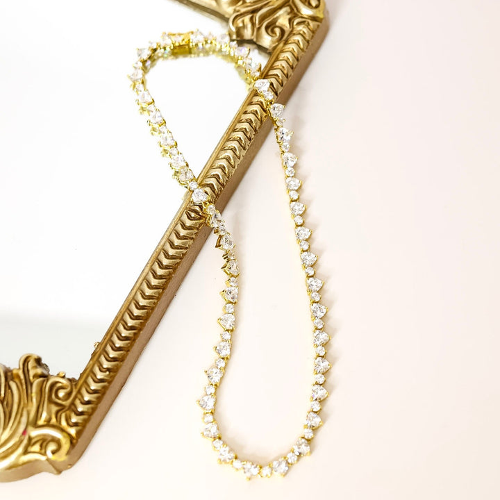 Gold heart necklace with decorative clasp and crystal heart and circles. 