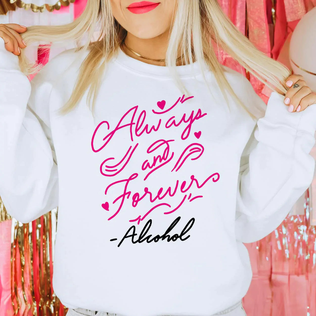 This white sweatshirt has a cursive graphic that says "Always and Forever" - Alcohol in hot pink and black. The model is wearing it paired with a gold choker-like necklace.