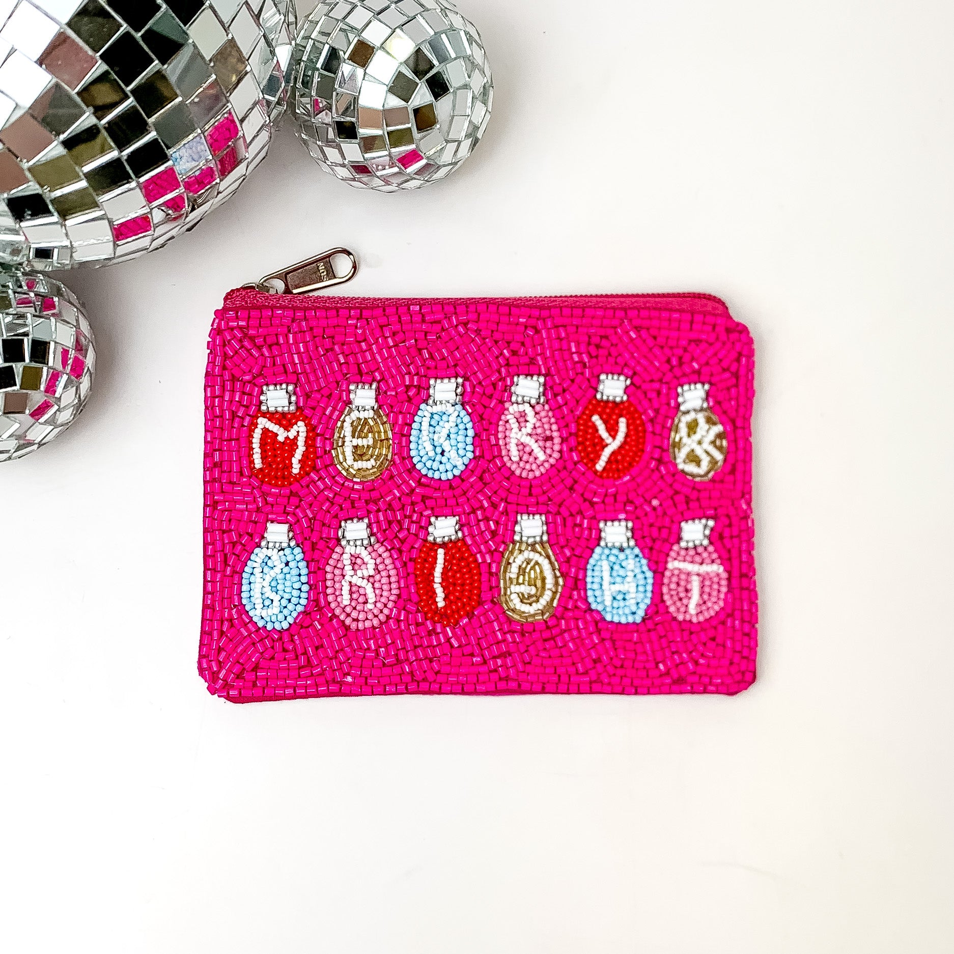 Fuchsia beaded coin purse with multicolored christmas lights. In each light there is a letter and the letters spell out MERRY & BRIGHT. This coin purse is pictured on a white background with disco balls in the top left corner. 
