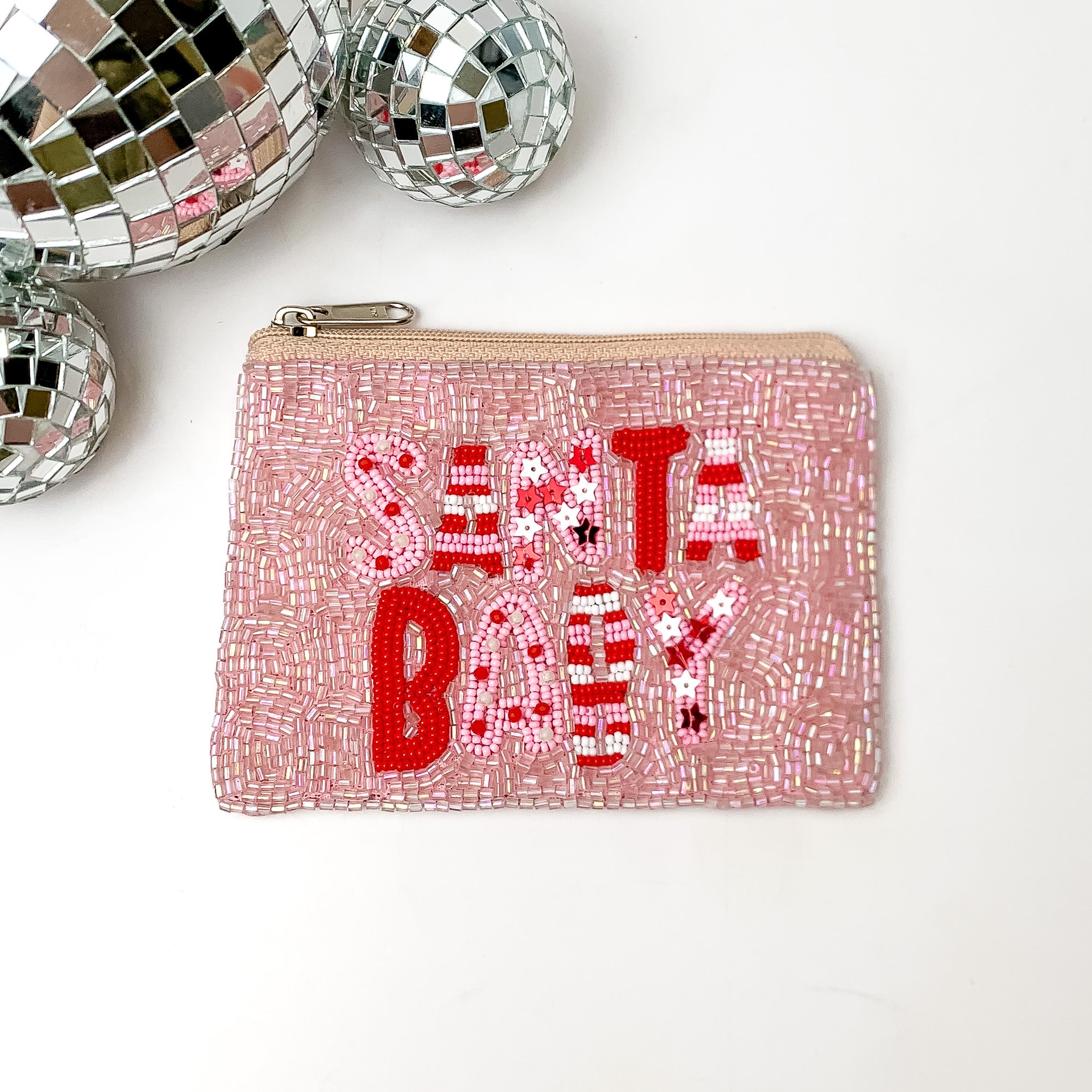 Light pink beaded coin purse with the words SANTA BABY. The letters are decorated in pink and red beads. This coin purse is pictured on a white background with disco balls in the top left corner. 