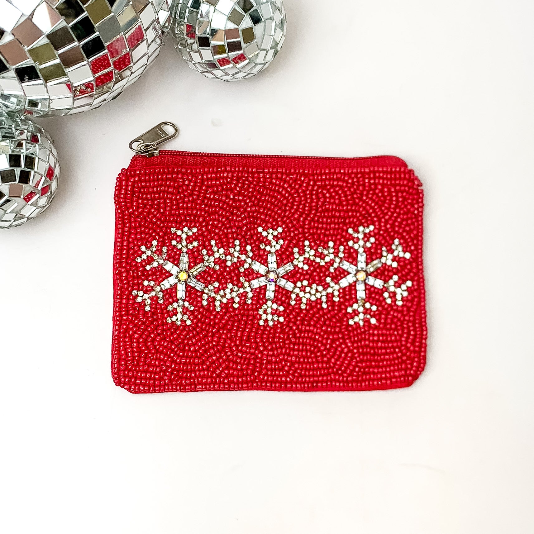 Red beaded coin purse with silver snowflakes through the center. This coin purse is pictured on a white background with disco balls in the top left corner. 