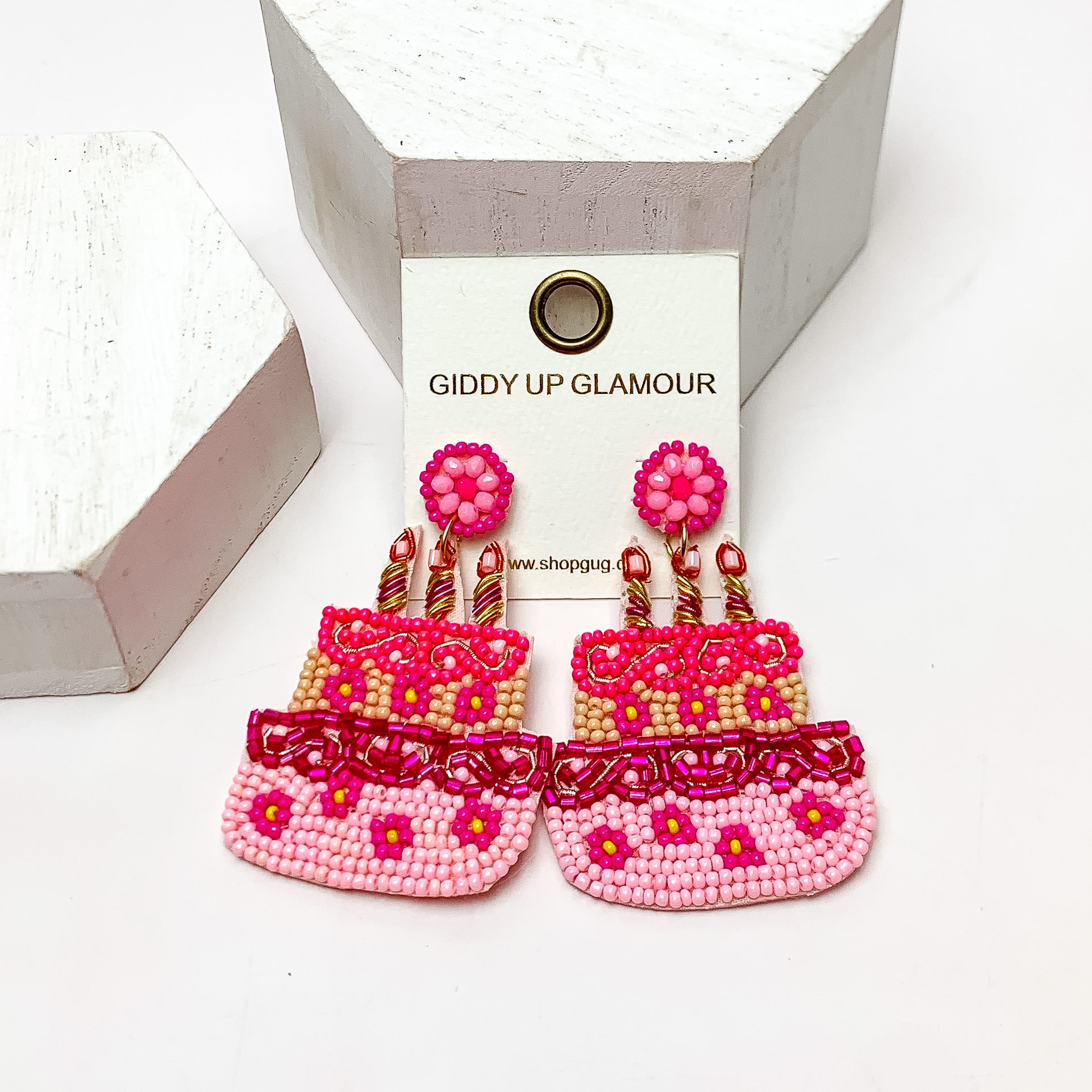 Birthday Cake Beaded Earrings in Hot Pink. These earrings are on a white background and have white posts around them.