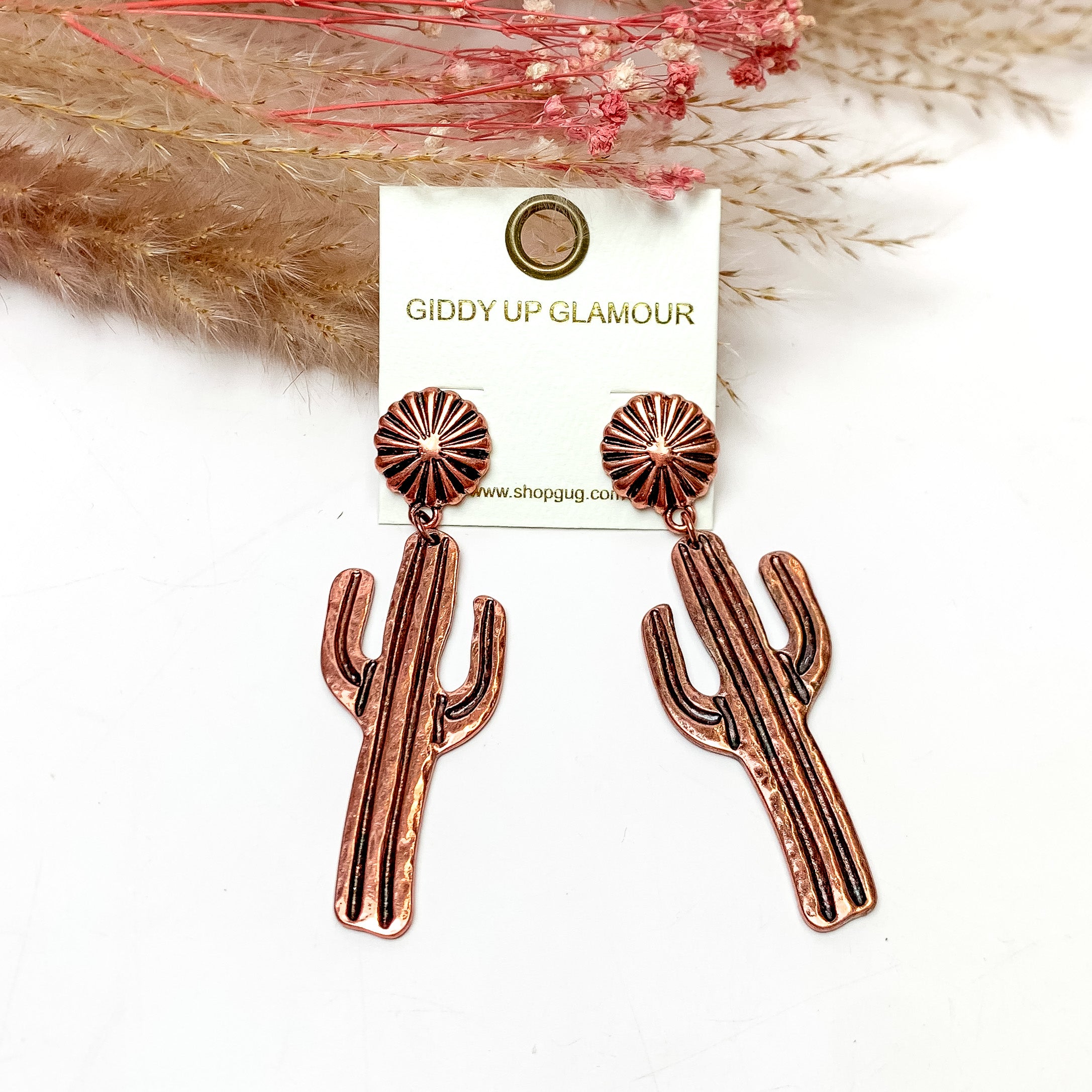 Country cactus copper tone earrings. These earrings are pictured on a white background with plants behind for decoration.