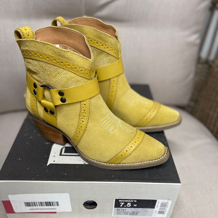 Yellow suede ankle cowboy boots with a harness strap, studs and a stacked wooden heel.