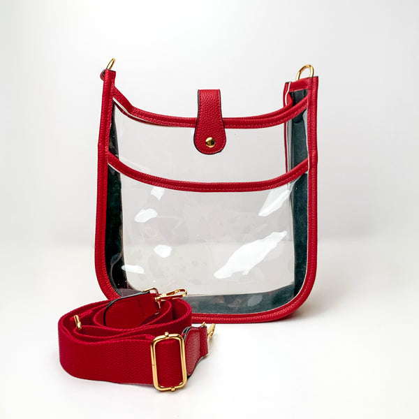 Clear crossbody purse in red with a red purse strap pictured in front of the purse. This purse is pictured on a white background. 