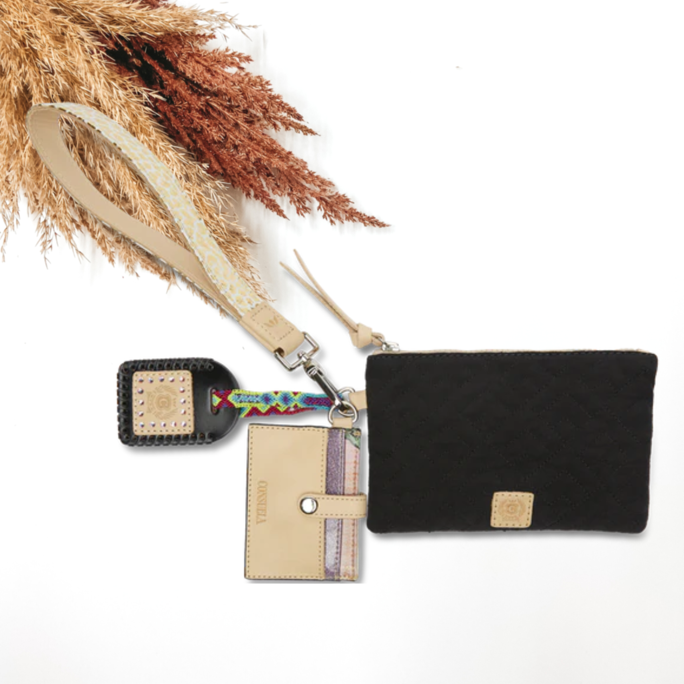 Pictured on a white background is a black pouch with a gold leopard print wristlet. This pouch also includes a a black luggage tag, light tan tassel on the zipper, and a card holder keychain.