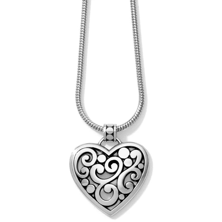 Silver heart-shaped pendant with intricate designs on a white background