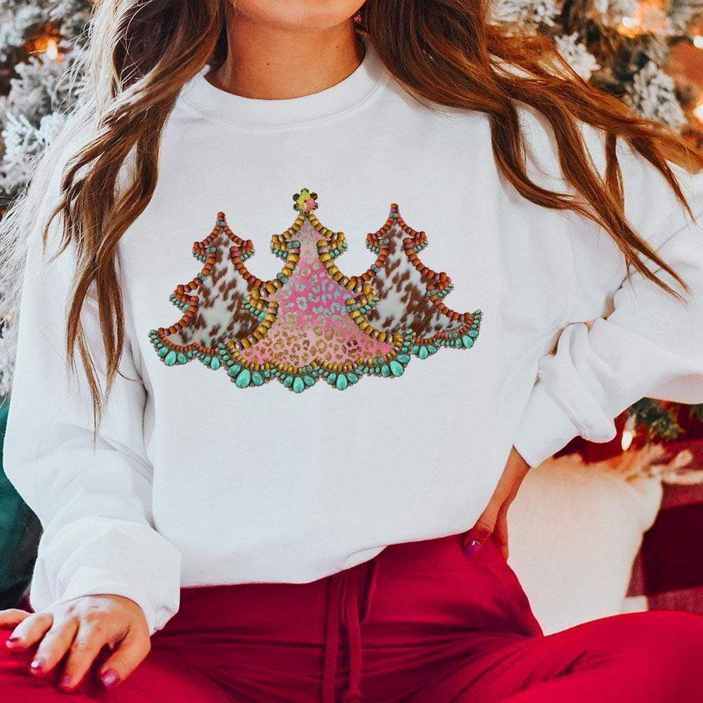 This white sweatshirt includes a crew neckline, long sleeves, and a cute Christmas graphic of three cowhide Christmas trees. The model has it styled here with red pants. 