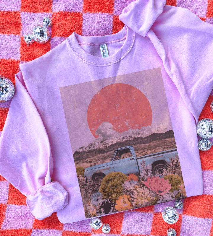 Purple sweatshirt with a graphic design of a sunset, truck, and landscape on a red and pink checkered background.