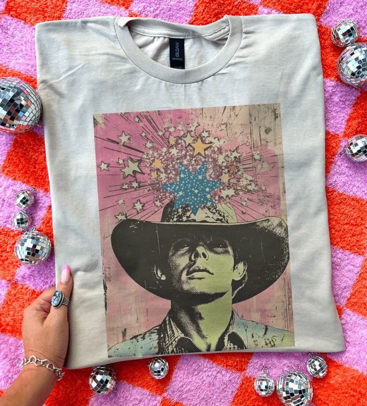 White t-shirt with a graphic design of a person wearing a hat on a colorful textured background