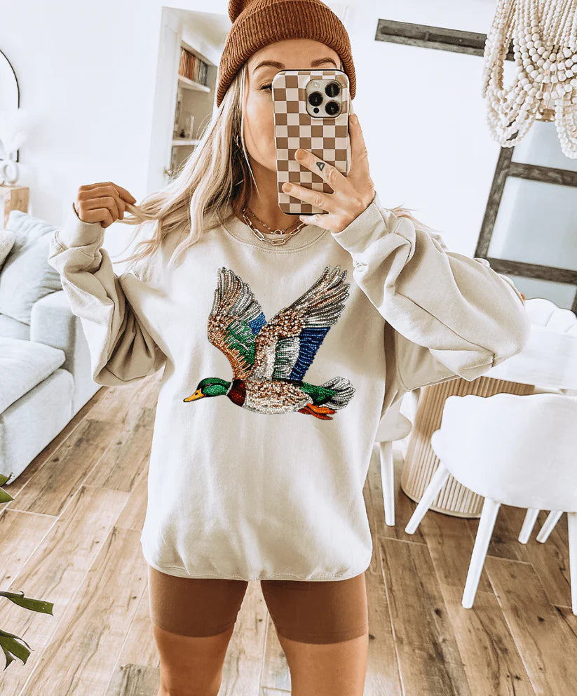 Person wearing a white sweatshirt with a duck graphic in a home setting