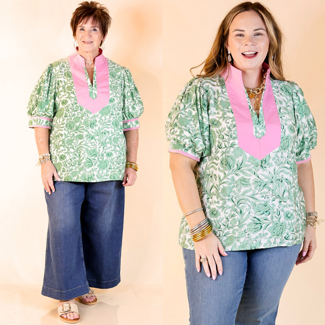 Green floral print top with short puff sleeves and pink accents on the collar, around the neck, and on the end of the sleeves. Featuring a plus size model.