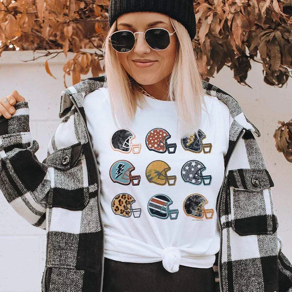 Model is wearing a white short sleeve crewneck tee featuring a graphic of 9 football helmets, each with their unique pattern.