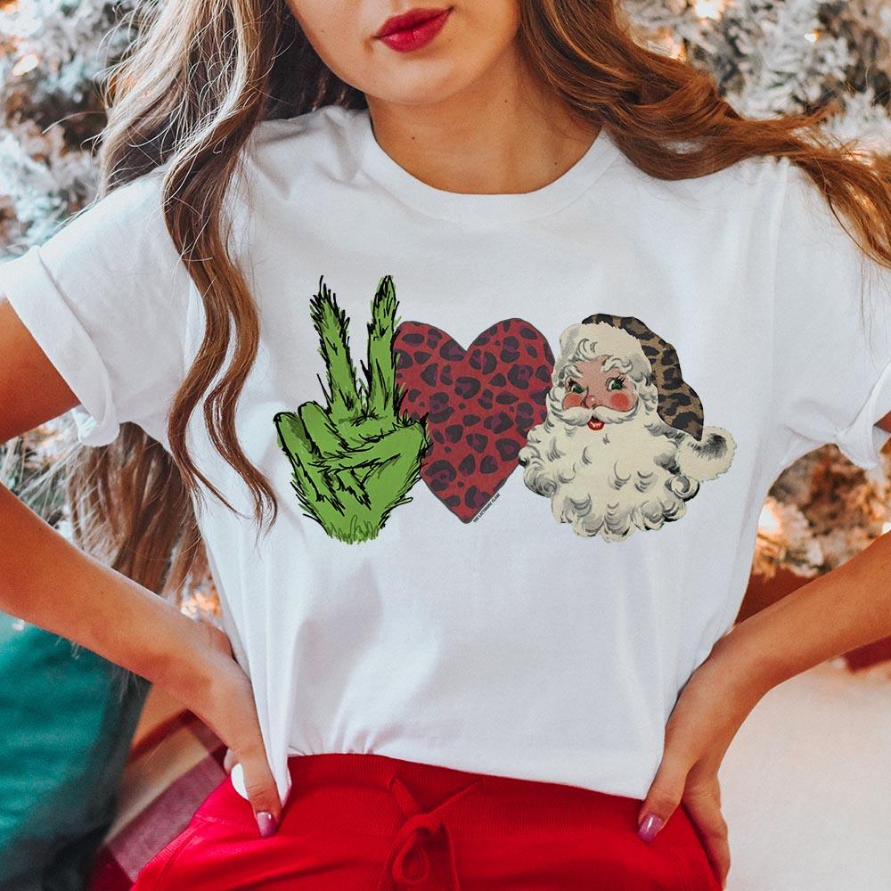 This top includes a crew neckline, short sleeves, and a cute Christmas graphic of a grinch hand holding up a peace sign, a red + leopard heart, and Santa Clause with a leopard hat. The model has this graphic tee styled with the sleeves rolled and with red pants. 