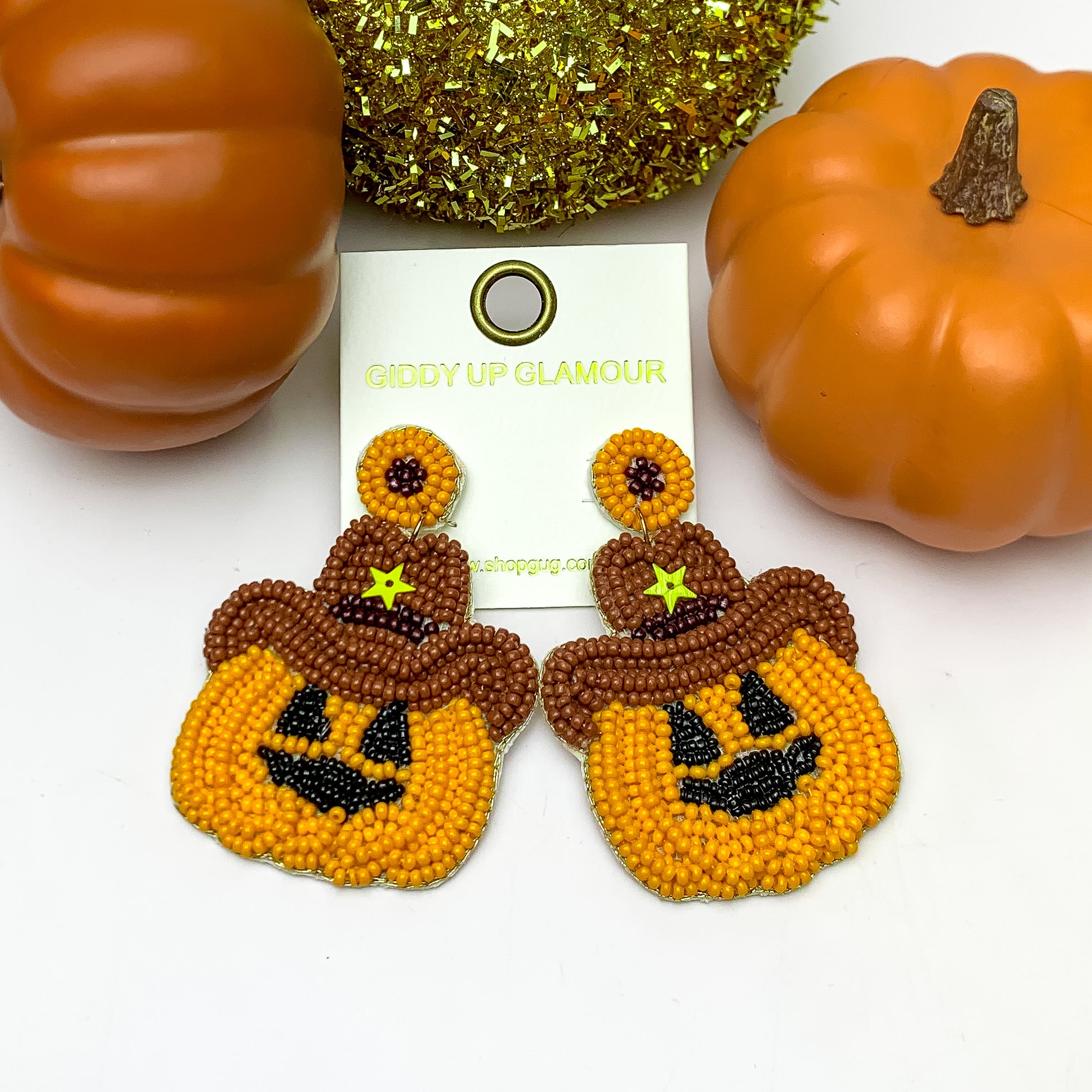 Beaded Pumpkin Earrings With Brown Cowboy Hat. These earrings are pictured on a white background with pumpkins behind the earrings.