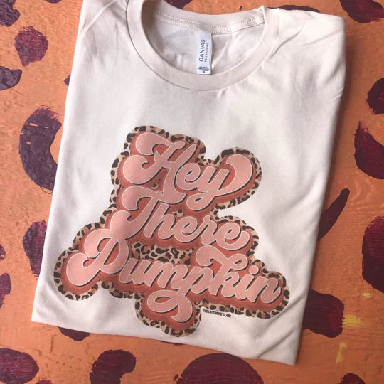 Cream graphic tee with the words hey there pumpkin in pink surrounded by a leopard print pattern. 