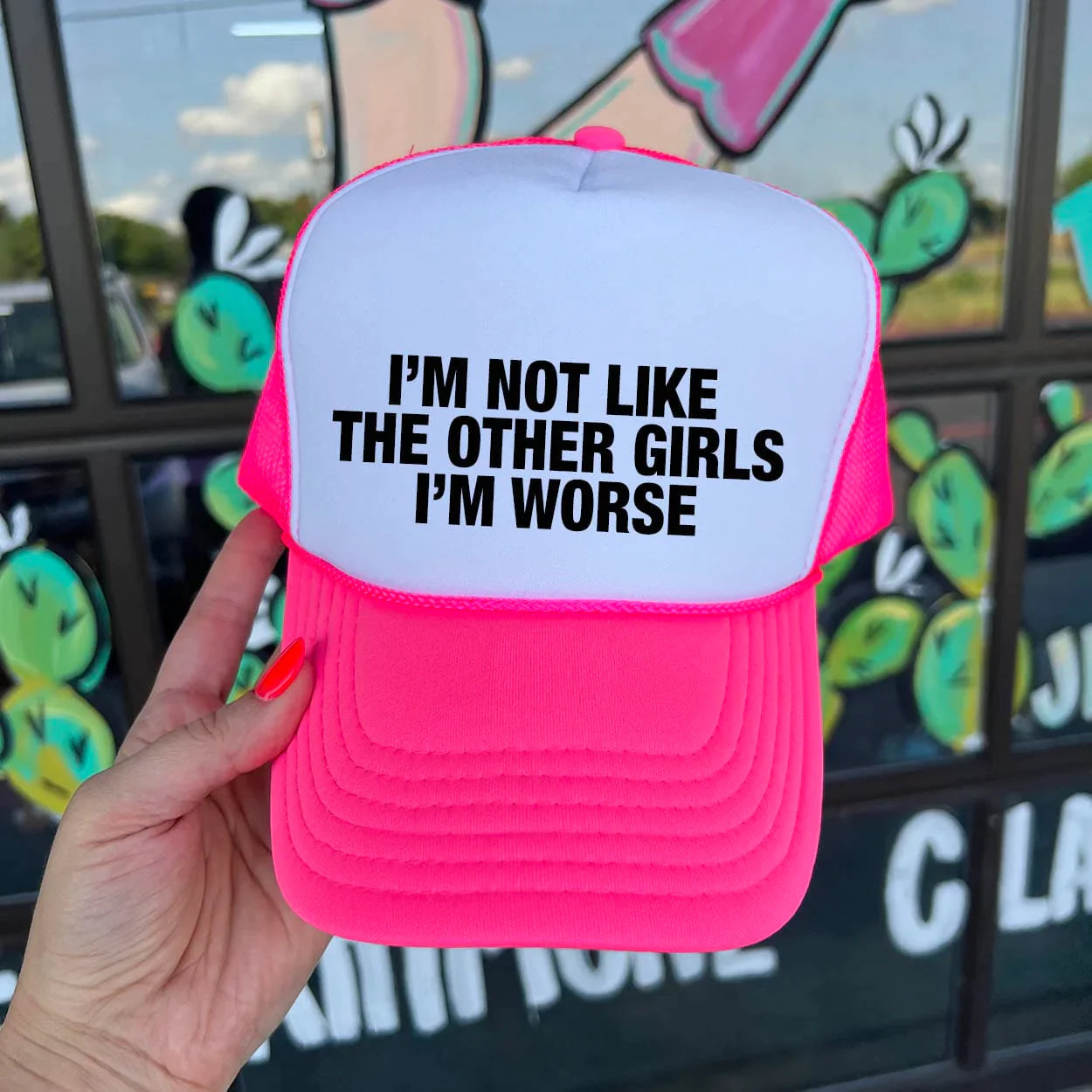 In the picture is a hot pink and white trucker cap that says I'm not like other girls I'm worse 